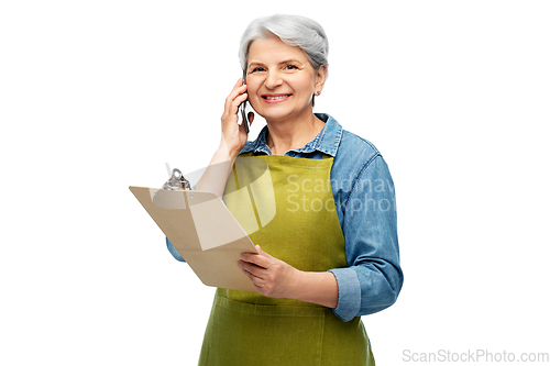 Image of old female gardener with clipboard calls on phone