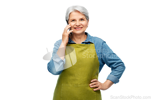 Image of senior woman in garden apron calling on smartphone