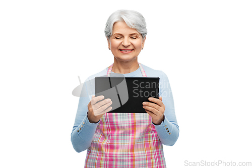 Image of smiling senior woman in apron with tablet computer