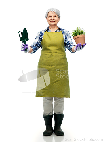 Image of old woman in apron with flower and garden tools