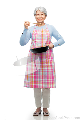 Image of smiling senior woman in apron with frying pan