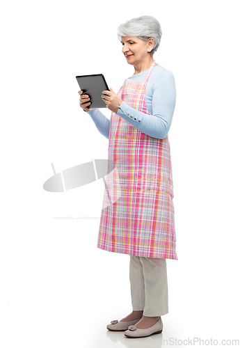 Image of smiling senior woman in apron with tablet computer