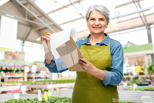 Image of smiling old woman with clipboard at garden store