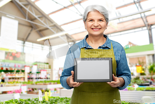 Image of happy senior woman with tablet pc at garden store