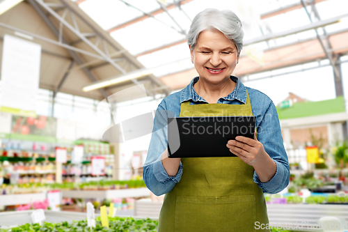 Image of happy senior woman with tablet pc at garden store