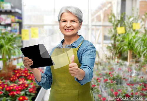 Image of happy senior woman with tablet pc at garden store