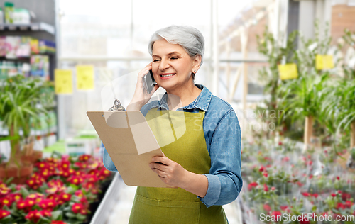 Image of old female gardener with clipboard calls on phone