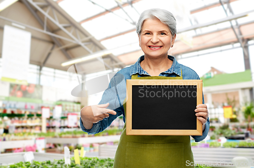 Image of happy senior woman with chalkboard at garden store