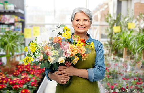Image of smiling senior woman with flowers at garden store