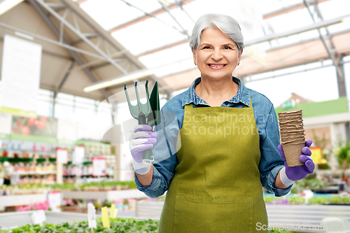 Image of old woman with pots and tools at garden store