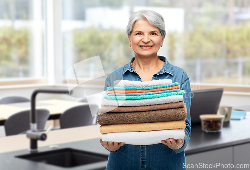 Image of happy senior woman with clean bath towels at home