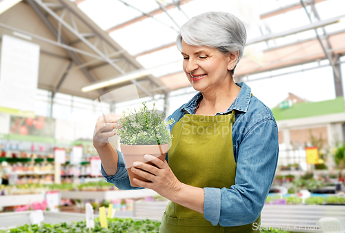 Image of smiling senior woman with flower at garden store