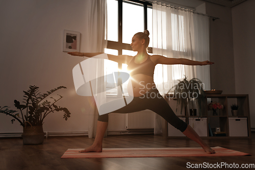 Image of pregnant woman doing yoga at home over sunshine