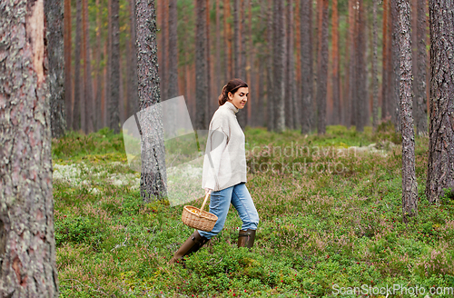 Image of woman with basket picking mushrooms in forest