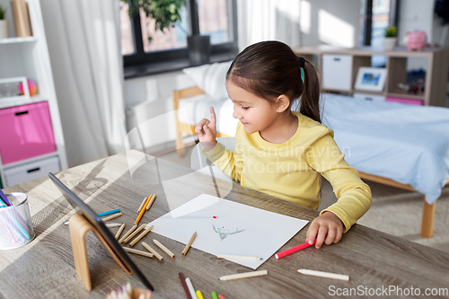 Image of little girl drawing with coloring pencils at home