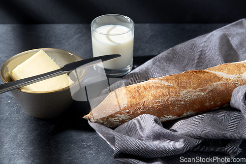 Image of close up of bread, butter, knife and glass of milk