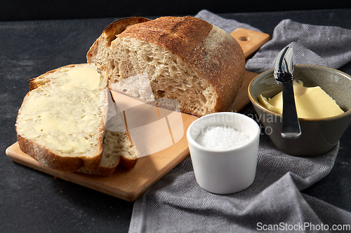 Image of close up of bread, butter, knife and salt on towel