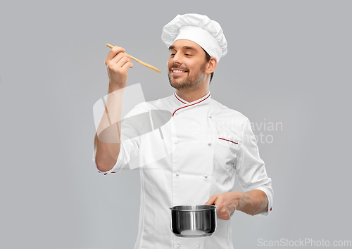 Image of happy smiling male chef with saucepan tasting food