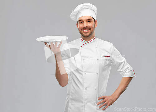 Image of happy smiling male chef holding empty plate