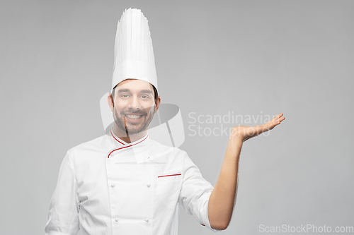 Image of happy smiling male chef holding something on hand