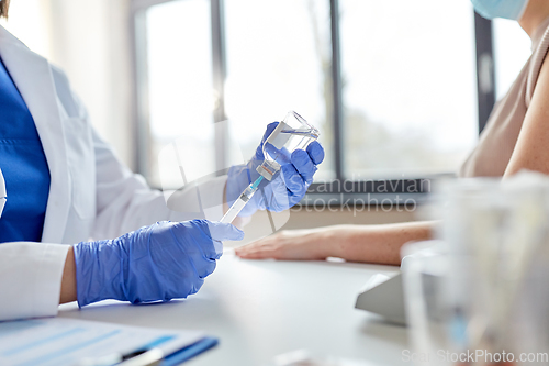 Image of female doctor with syringe vaccinating patient