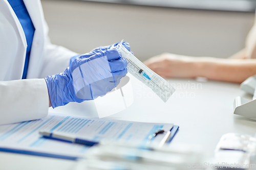 Image of female doctor with syringe and patient at hospital