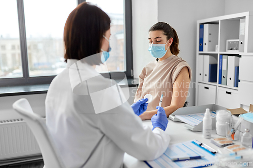 Image of female doctor with syringe vaccinating patient