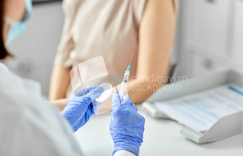 Image of female doctor with syringe vaccinating patient