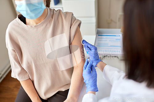 Image of female doctor with syringe vaccinating patient