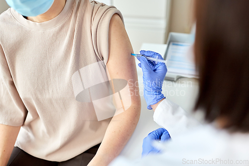 Image of female doctor with syringe vaccinating patient