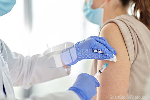 Image of female doctor with syringe vaccinating patient