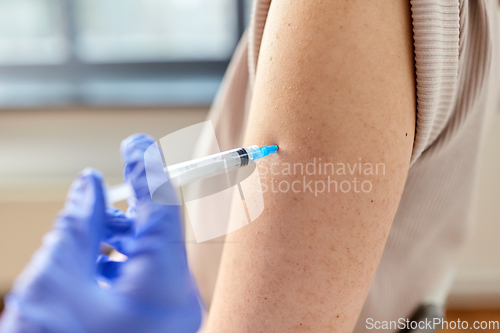 Image of close up of hand with syringe vaccinating patient