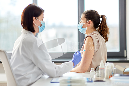 Image of female doctor with syringe vaccinating patient