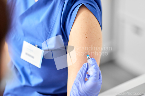 Image of doctor with syringe vaccinating medical worker