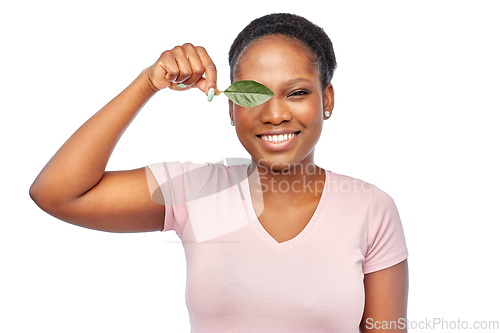 Image of smiling african american woman holding green leaf