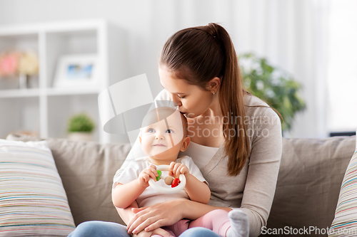 Image of mother kissing baby with teething toy at home