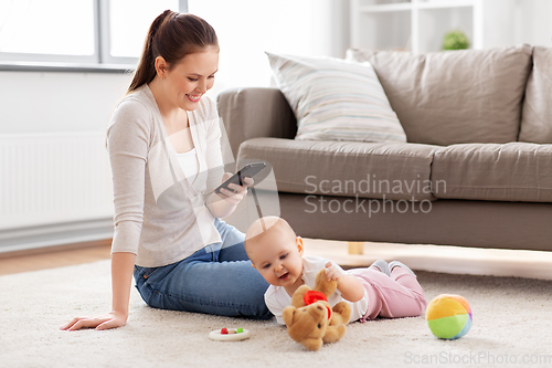 Image of mother with smartphone and baby playing at home