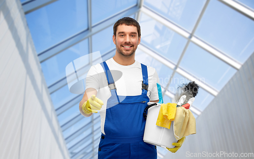 Image of male cleaner in overall with cleaning supplies