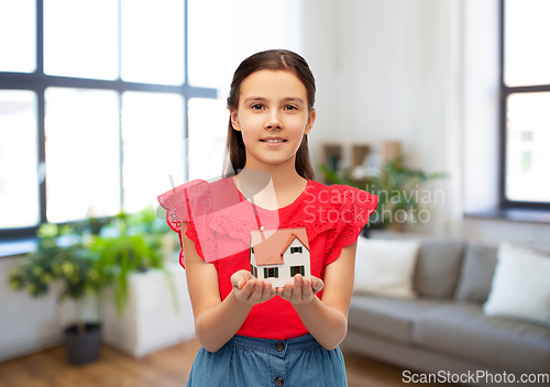 Image of smiling girl holding house model at home