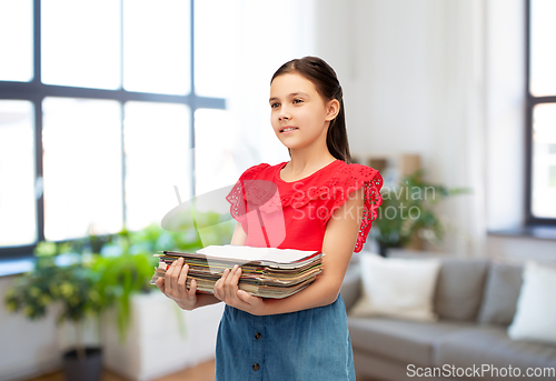 Image of girl with magazines sorting paper waste at home