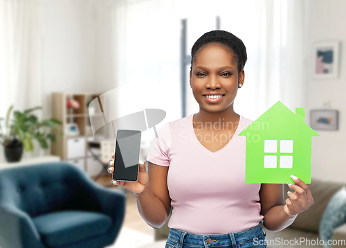 Image of african woman with smartphone and green house