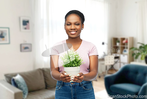 Image of happy smiling african woman holding flower in pot