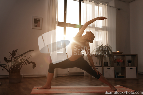 Image of pregnant woman doing yoga at home over sunshine