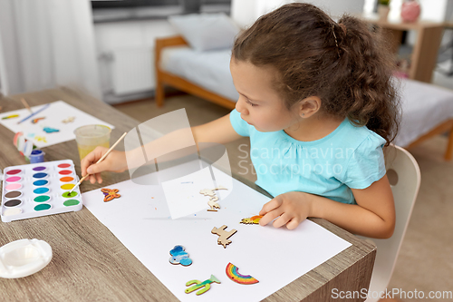 Image of little girl painting wooden items at home