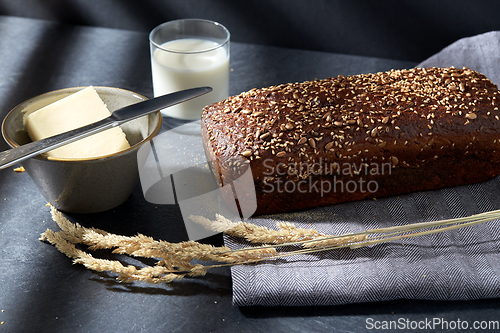 Image of close up of bread, butter, knife and glass of milk