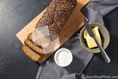 Image of close up of bread, butter, knife and salt on towel