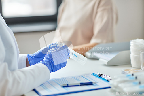 Image of female doctor with syringe and patient at hospital