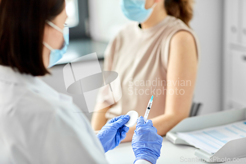Image of female doctor with syringe vaccinating patient