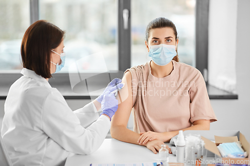 Image of female doctor with syringe vaccinating patient