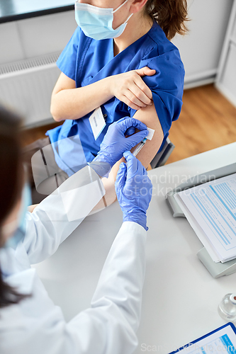 Image of doctor with syringe vaccinating medical worker